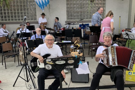 A bass player and accordionist smile in front of some members of the band.