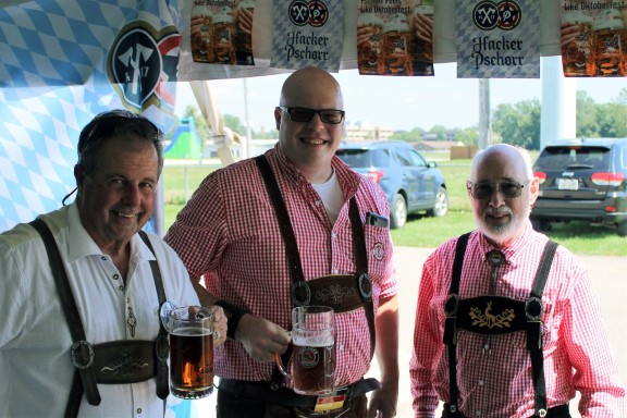 Three men in lederhosen, smiling and posing together